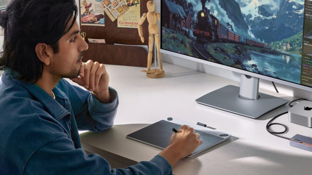 A man sitting at a desk with a computer and a tablet